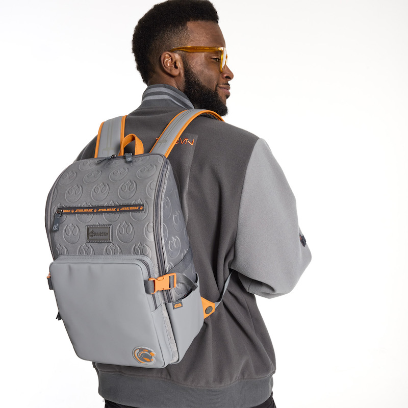 Man facing away from camera wearing the Loungefly COLLECTIV Star Wars Rebel Alliance VRSITY Jacket and The MULTI-TASKR Full Size Backpack, which features debossed Rebel Alliance symbols all over it with highlights of orange on the straps, handle, and buckles. 